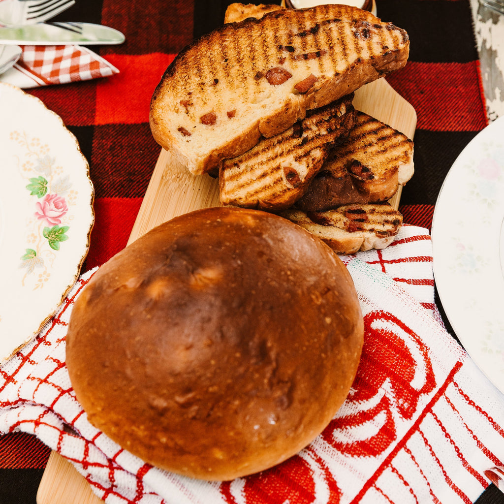 Pain maison grillé et pain fesse servis sur une table cabane à sucre avec nappe carreautée – La Bine Mascouche